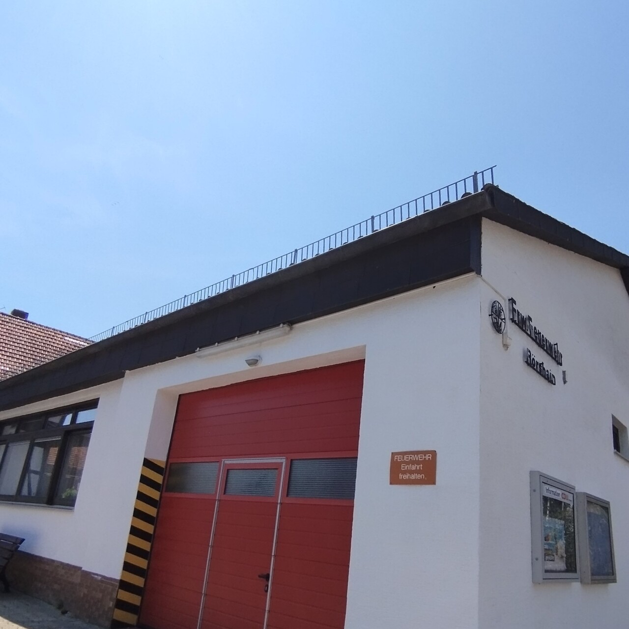 Gemeinschaftshaus Rörshain, Aussenansicht, weisses Gebäude mit einer roten Tor für die Fahrzeuge der Feuerwehr